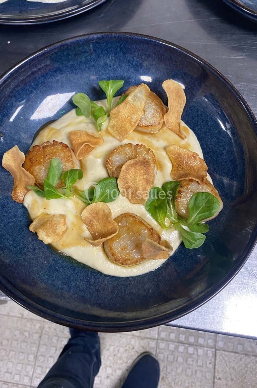 Assiette de purée crémeuse garnie de tranches de légumes rôtis, chips croustillantes et feuilles de mâche.