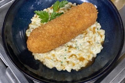 Miniature Location salle Rueil-Malmaison (Hauts-de-Seine) - Espace Laplace #26 Assiette de velouté orange garnie de croûtons dorés et de traits de crème blanche, servie sur une table en inox.