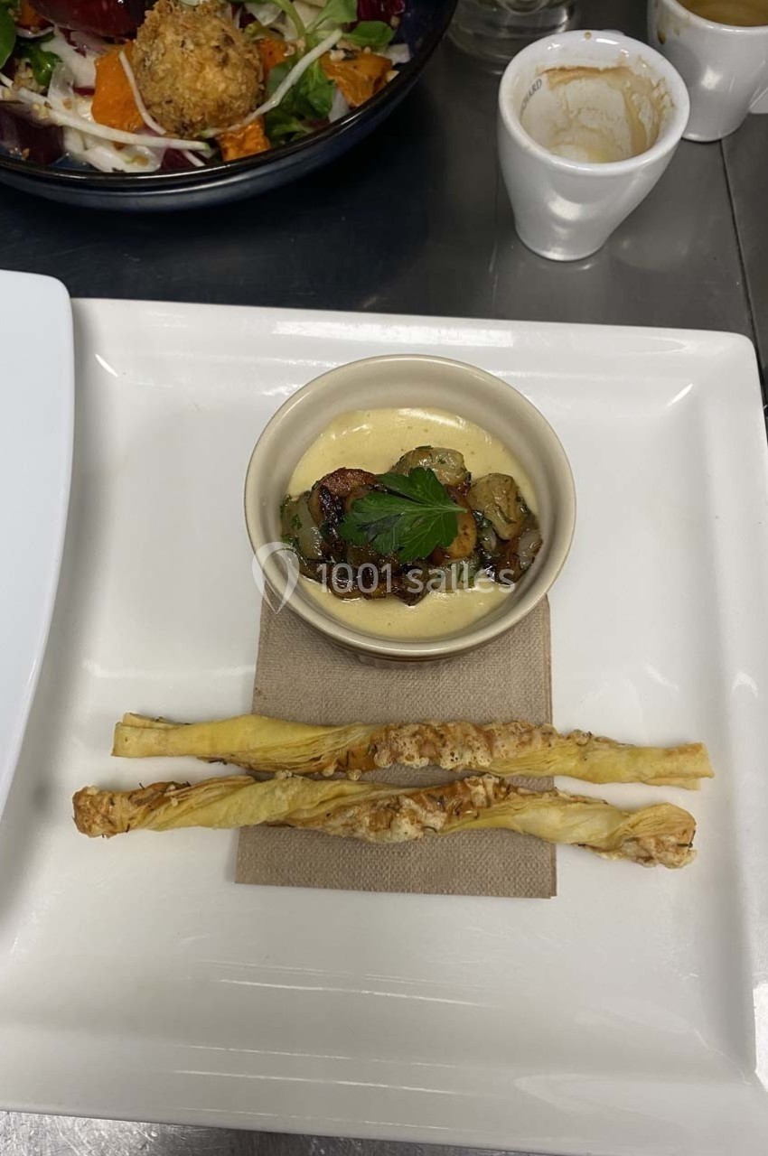 Assiette avec une verrine de crème garnie de légumes, accompagnée de trois gressins torsadés.