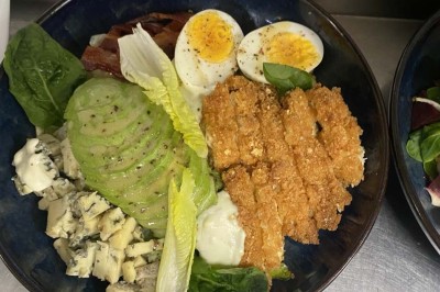 Miniature Location salle Rueil-Malmaison (Hauts-de-Seine) - Espace Laplace #29 Assiette de velouté orange garnie de croûtons dorés et de traits de crème blanche, servie sur une table en inox.