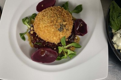 Miniature Location salle Rueil-Malmaison (Hauts-de-Seine) - Espace Laplace #30 Assiette de velouté orange garnie de croûtons dorés et de traits de crème blanche, servie sur une table en inox.