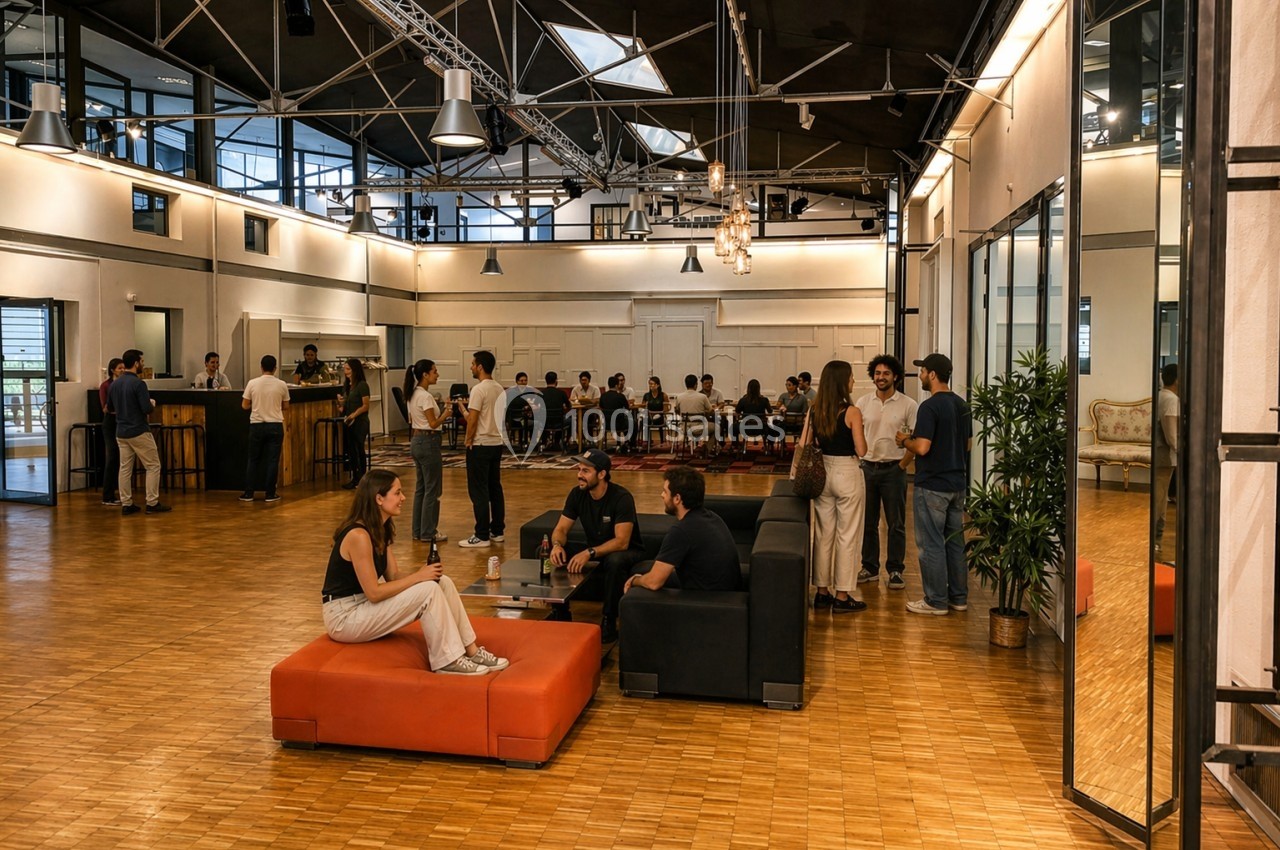 Personnes discutant et partageant un moment convivial dans un espace intérieur moderne avec mobilier et éclairage industriel.