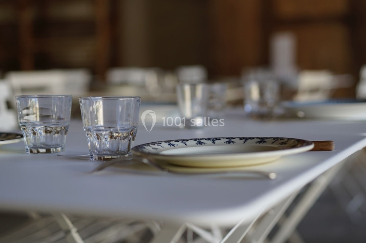 Table dressée avec des assiettes décorées, des verres en verre et des couverts sur une nappe blanche.