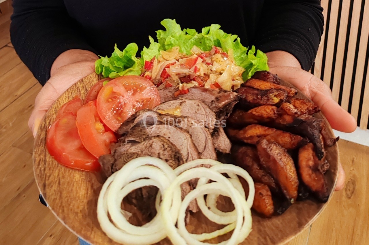 Assiette en bois contenant de la viande tranchée, des légumes frais, des rondelles d'oignon et des morceaux de viande…