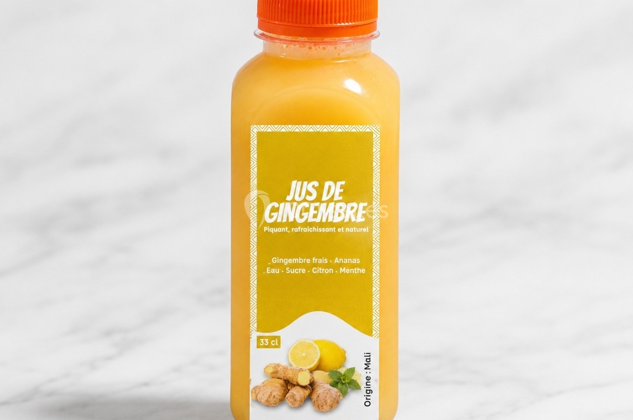 Bouteille de jus de gingembre avec ananas, citron et menthe, posée sur une surface en marbre clair.