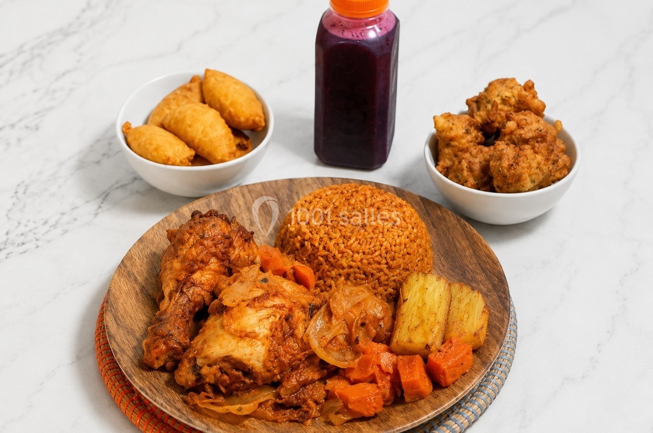 Assiette de riz épicé avec poulet, légumes, beignets et jus de fruits, disposés sur une table en marbre.