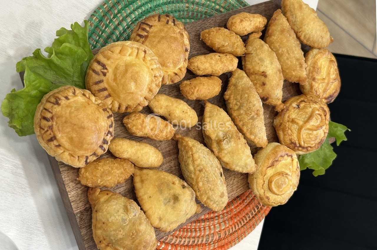 Assortiment de petits chaussons salés et feuilletés disposés sur un plateau en bois avec des feuilles de salade.