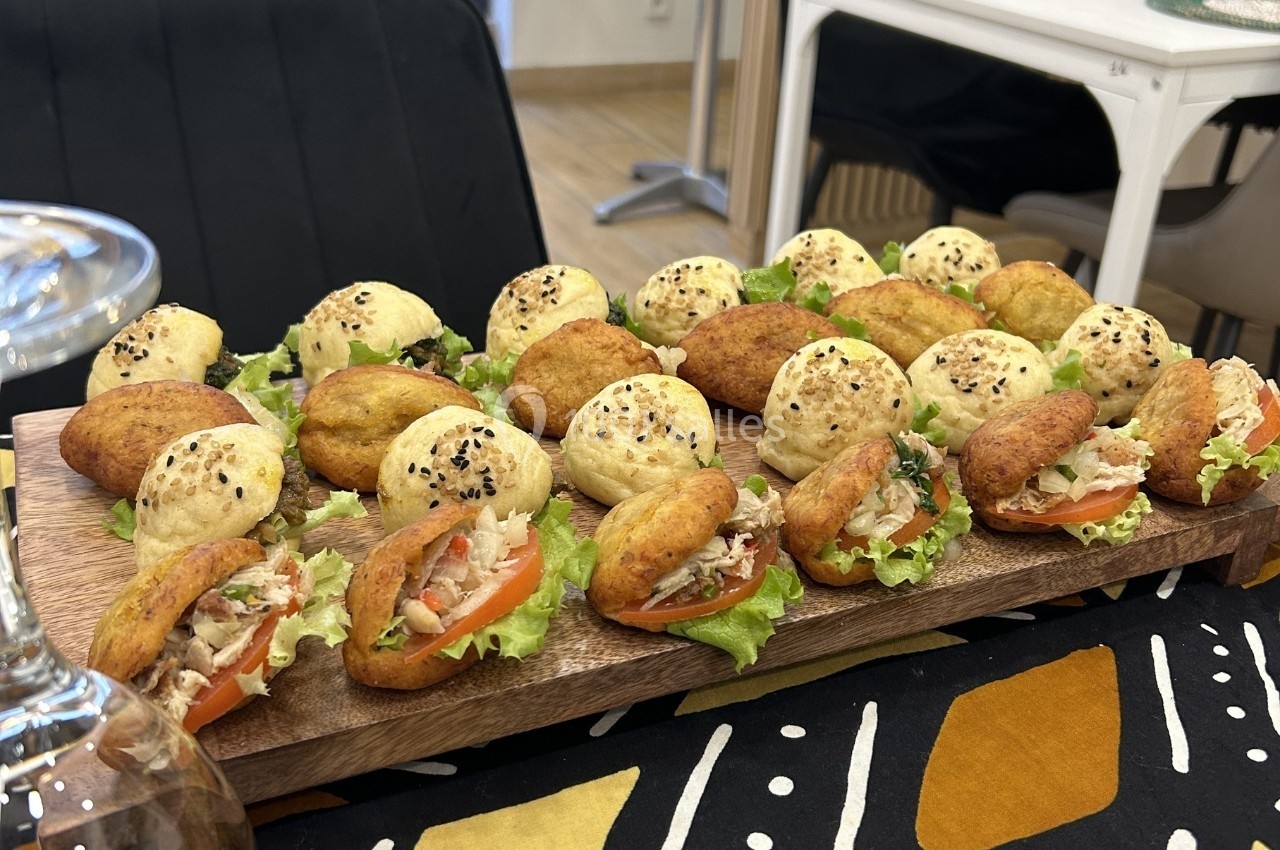 Plateau de mini-sandwichs variés avec garnitures de légumes, salade et pain garni de graines de sésame.