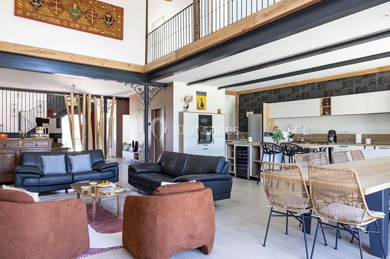Espace de vie lumineux avec salon, cuisine ouverte, table à manger et mezzanine, décoré dans un style moderne et chaleureux.