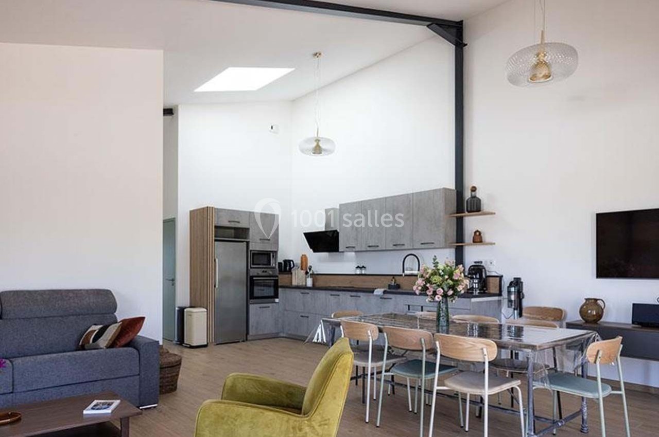 Salle à manger et cuisine ouverte modernes avec table, chaises, canapé, et décoration sobre dans un espace lumineux.