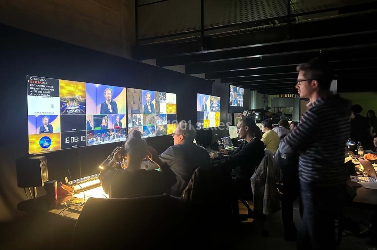 Techniciens supervisant des écrans de contrôle dans une régie audiovisuelle pendant un événement en direct.