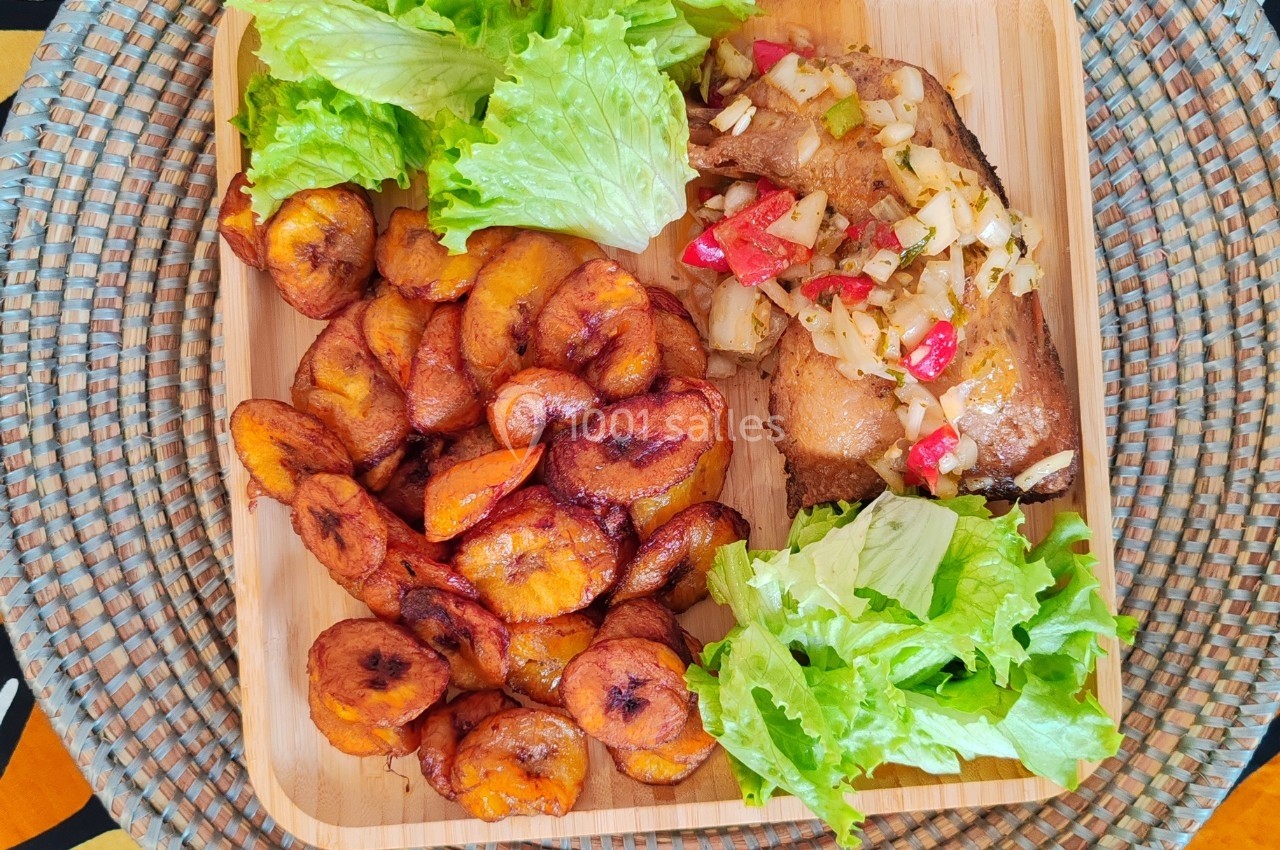 Assiette contenant des bananes plantains frites, une portion de poisson grillé avec légumes et de la salade verte.