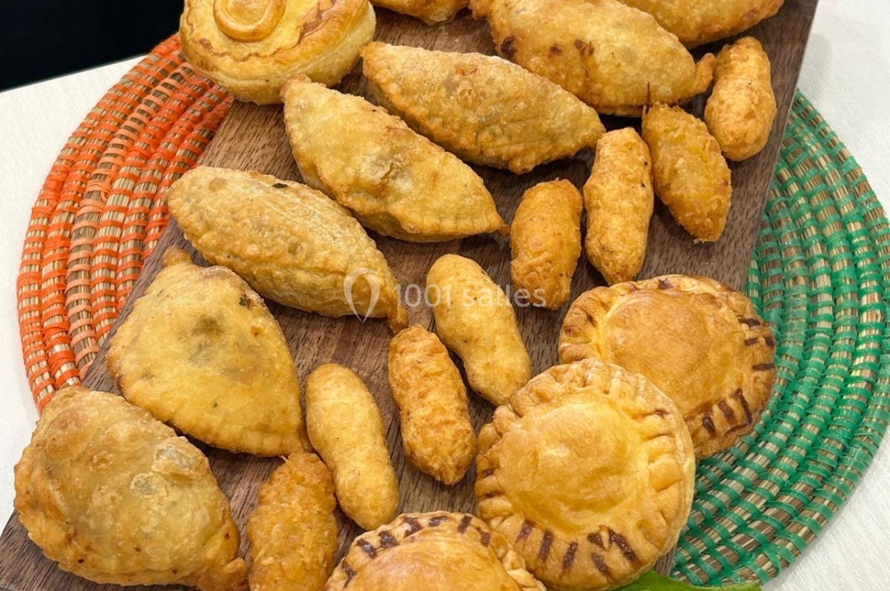 Assortiment de pâtisseries salées dorées, disposées sur une planche en bois avec des dessous colorés.