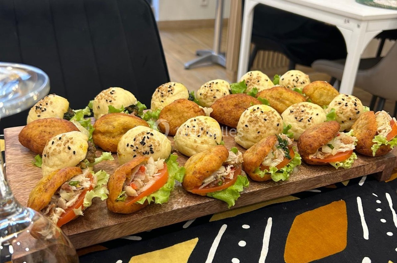 Plateau de mini-sandwichs variés garnis de légumes et de salade, disposés sur une planche en bois.