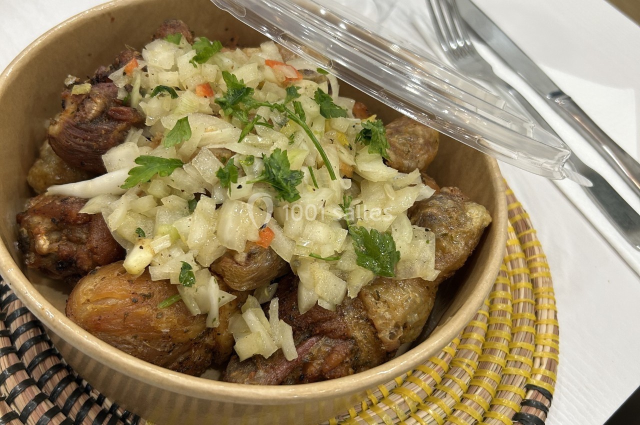 Plat de viande grillée accompagné de pommes de terre et garni d'oignons marinés et de persil dans un bol en carton.