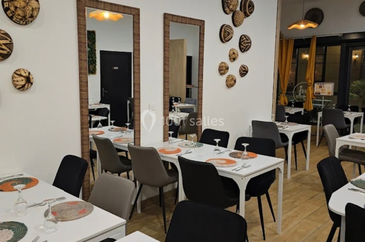 Salle de restaurant moderne avec tables dressées, chaises variées et décorations murales en osier.
