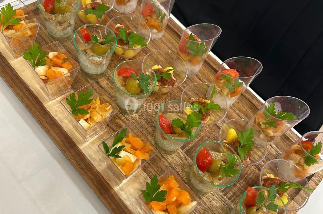Plateau en bois avec verrines garnies de légumes, herbes fraîches et cubes de fromage, disposées pour un buffet.