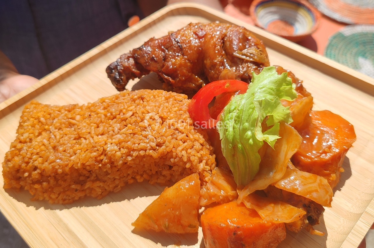 Assiette en bois contenant du riz, un morceau de poulet grillé, des légumes et des patates douces en sauce.