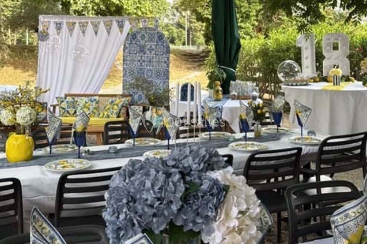 Table décorée pour une fête en extérieur, avec fleurs, vaisselle colorée et chiffres ’18’ en arrière-plan.