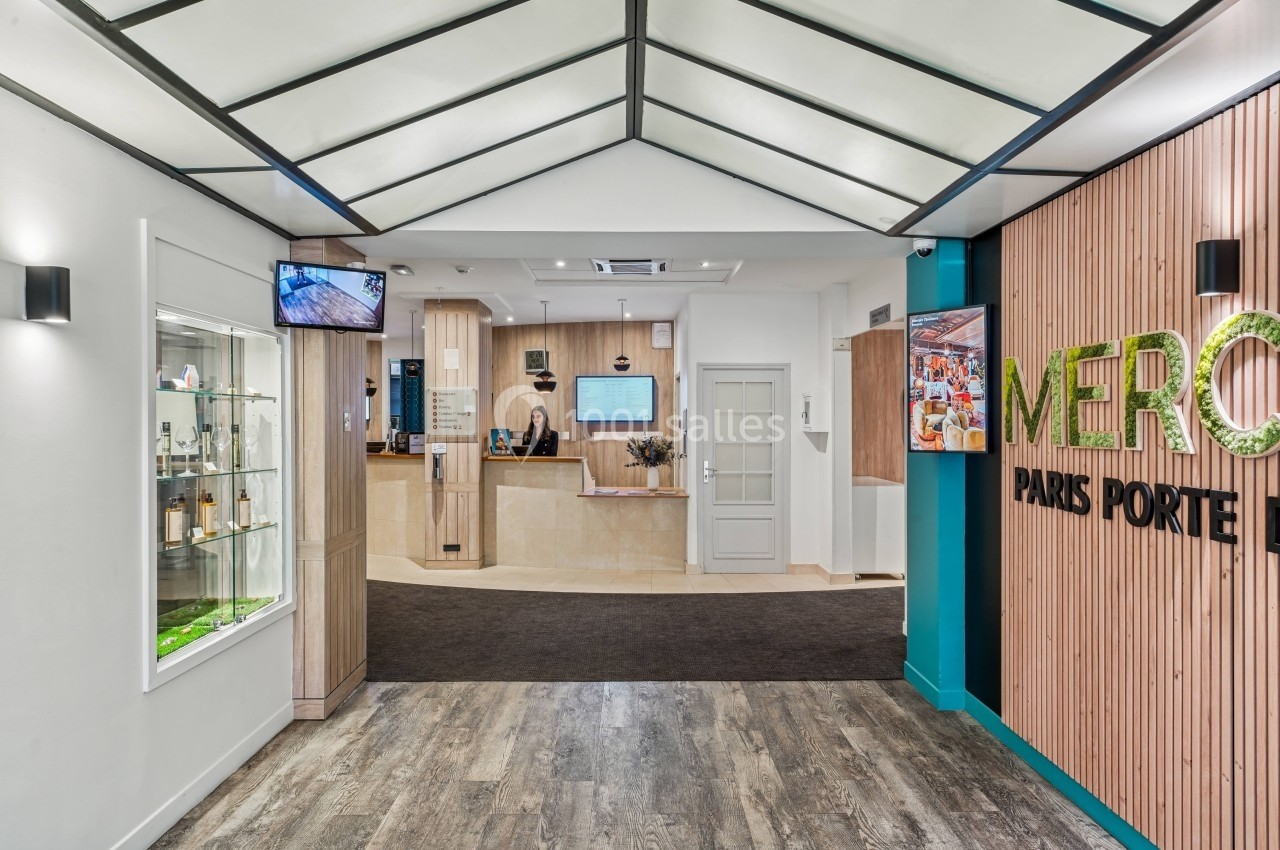 Hall d'entrée moderne avec comptoir de réception, sol en bois, murs décorés et éclairage contemporain.