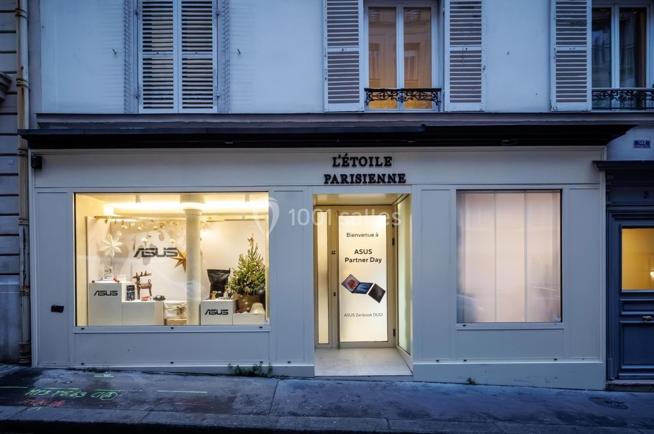 Façade d'une boutique avec vitrines éclairées, affichant des produits ASUS et un panneau ’ASUS Partner Day’.
