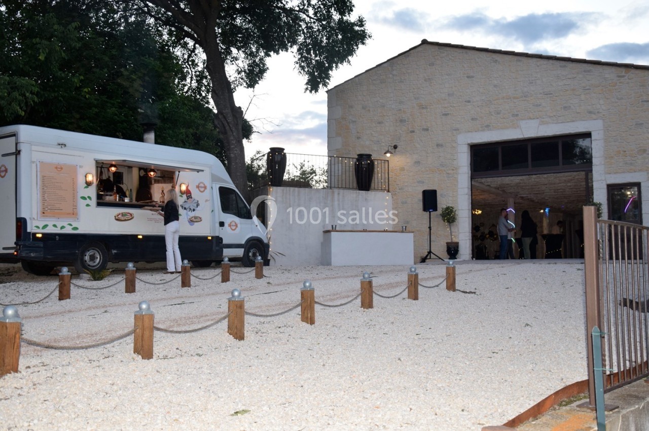 Camion de restauration stationné devant une salle en pierre avec des lumières allumées à l'intérieur.