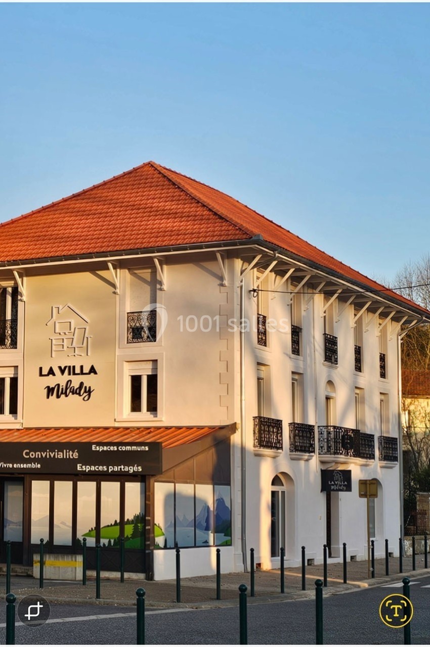 Façade d'un bâtiment moderne avec toit en tuiles rouges, balcons en fer forgé et enseigne ’La Villa Milady’.
