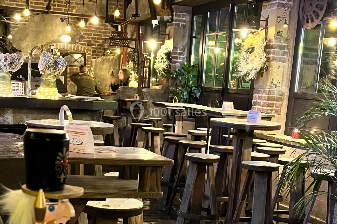 Intérieur d'un café chaleureux avec tables en bois, éclairage tamisé et décoration rustique.