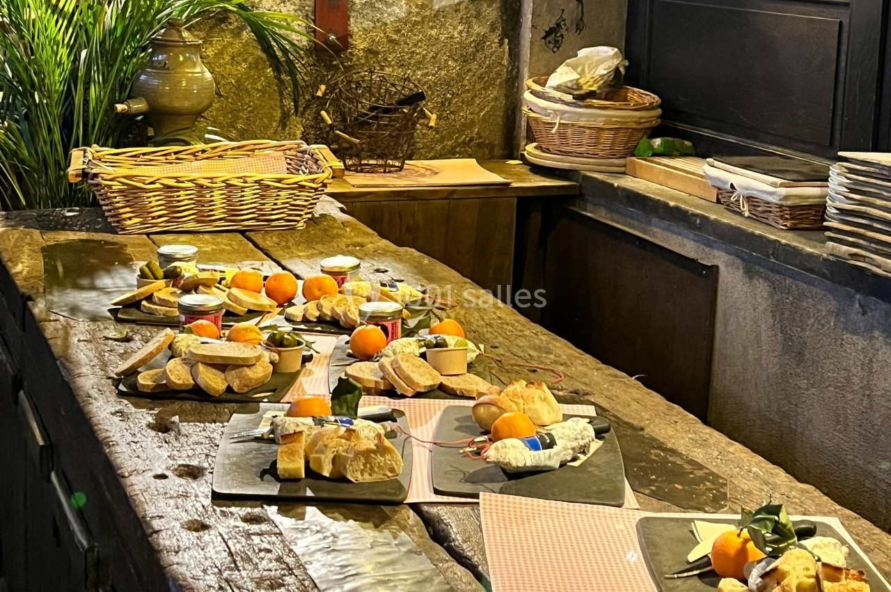 Plateaux de fromages, pains et fruits disposés sur une table en bois rustique dans un cadre chaleureux.