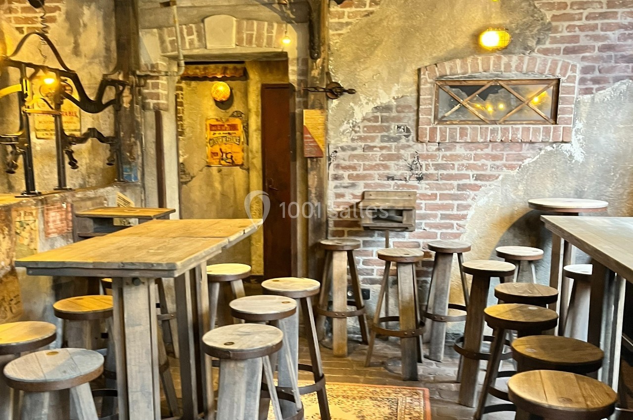 Intérieur d'un café rustique avec des murs en briques, des tabourets en bois et un éclairage chaleureux.