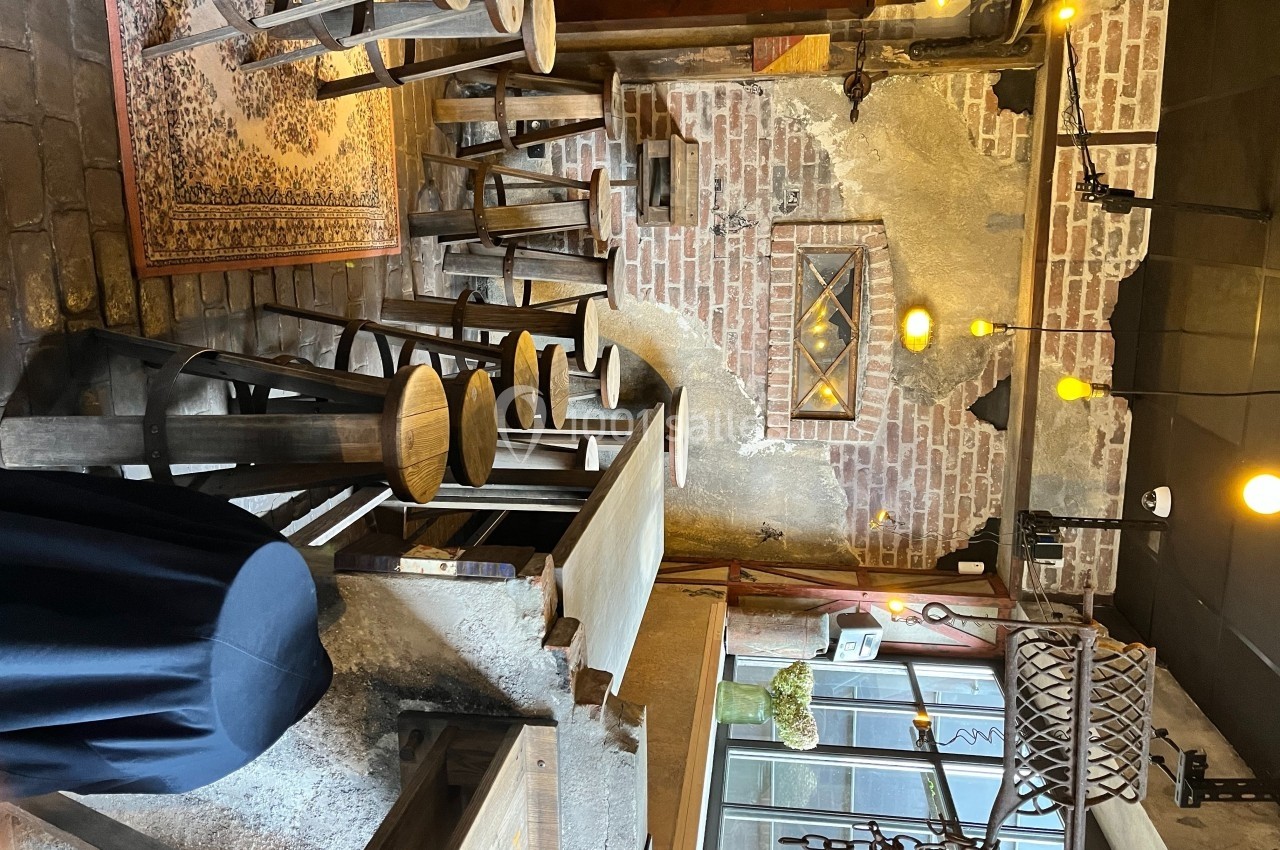 Intérieur d'un café rustique avec murs en briques, tabourets en bois, éclairage chaleureux et décorations vintage.