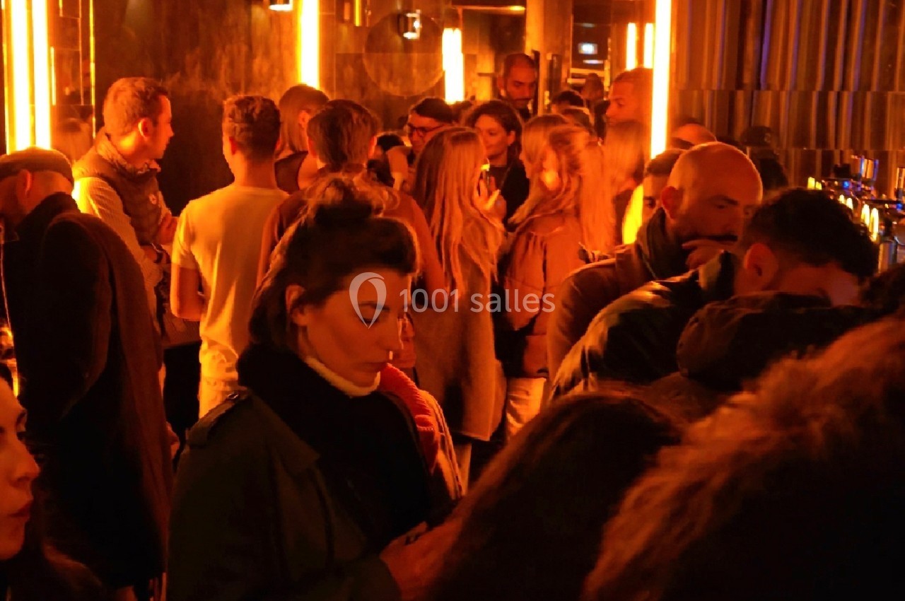 Groupe de personnes rassemblées dans un espace intérieur à l'éclairage tamisé et ambiance chaleureuse.