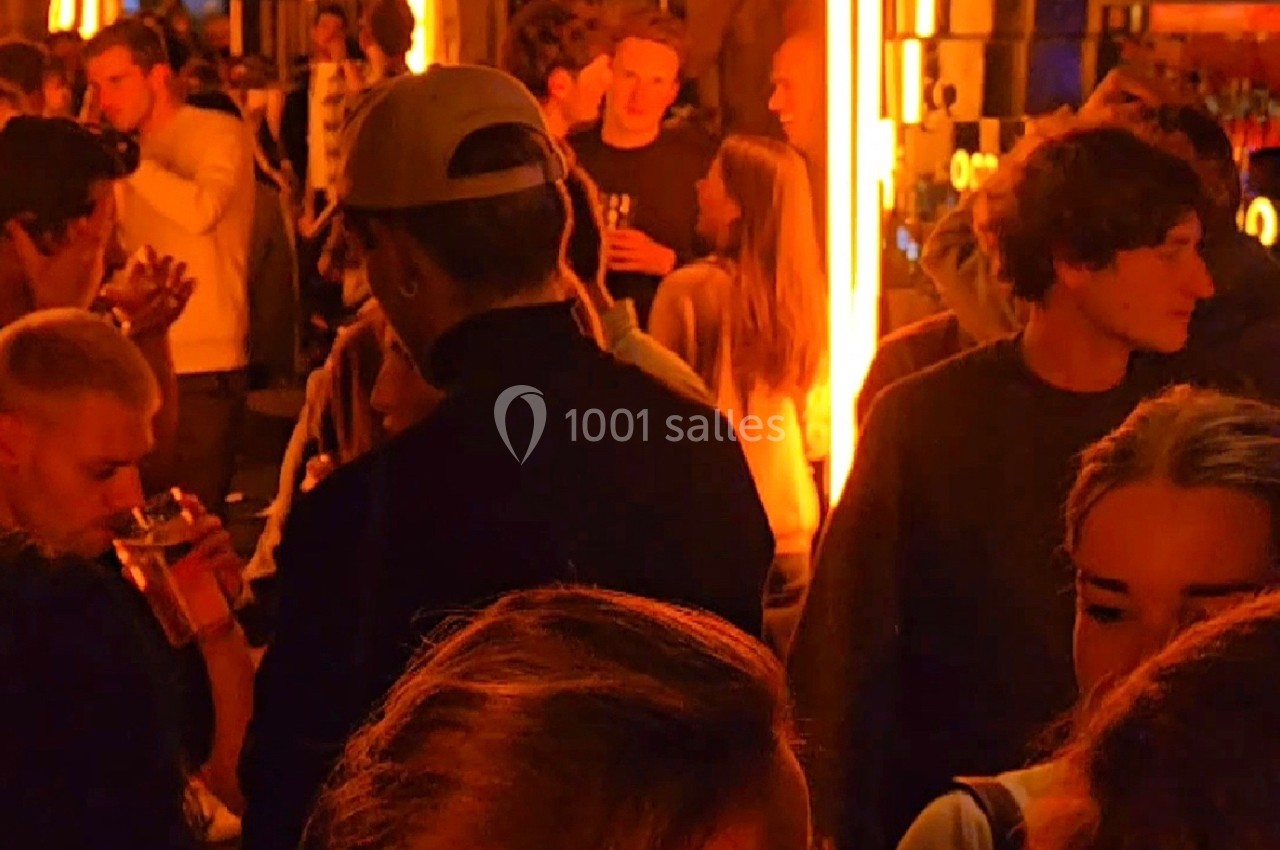 Groupe de personnes discutant et partageant un moment convivial dans un lieu éclairé par des lumières chaudes.