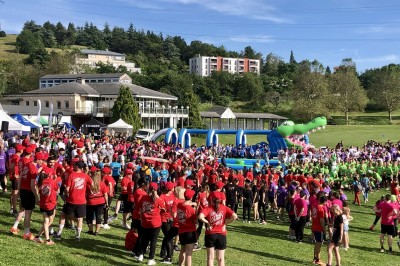 Un groupe de personnes en t-shirts verts participe à une activité de fléchettes géantes en plein air.