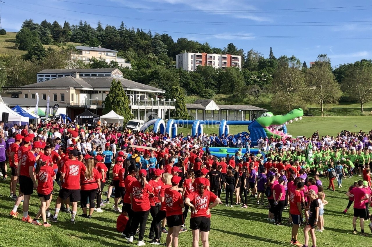 Un grand groupe de personnes participe à un événement en plein air avec structures gonflables et animations.