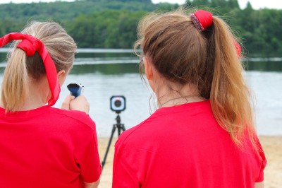 Un groupe de personnes en t-shirts verts participe à une activité de fléchettes géantes en plein air.