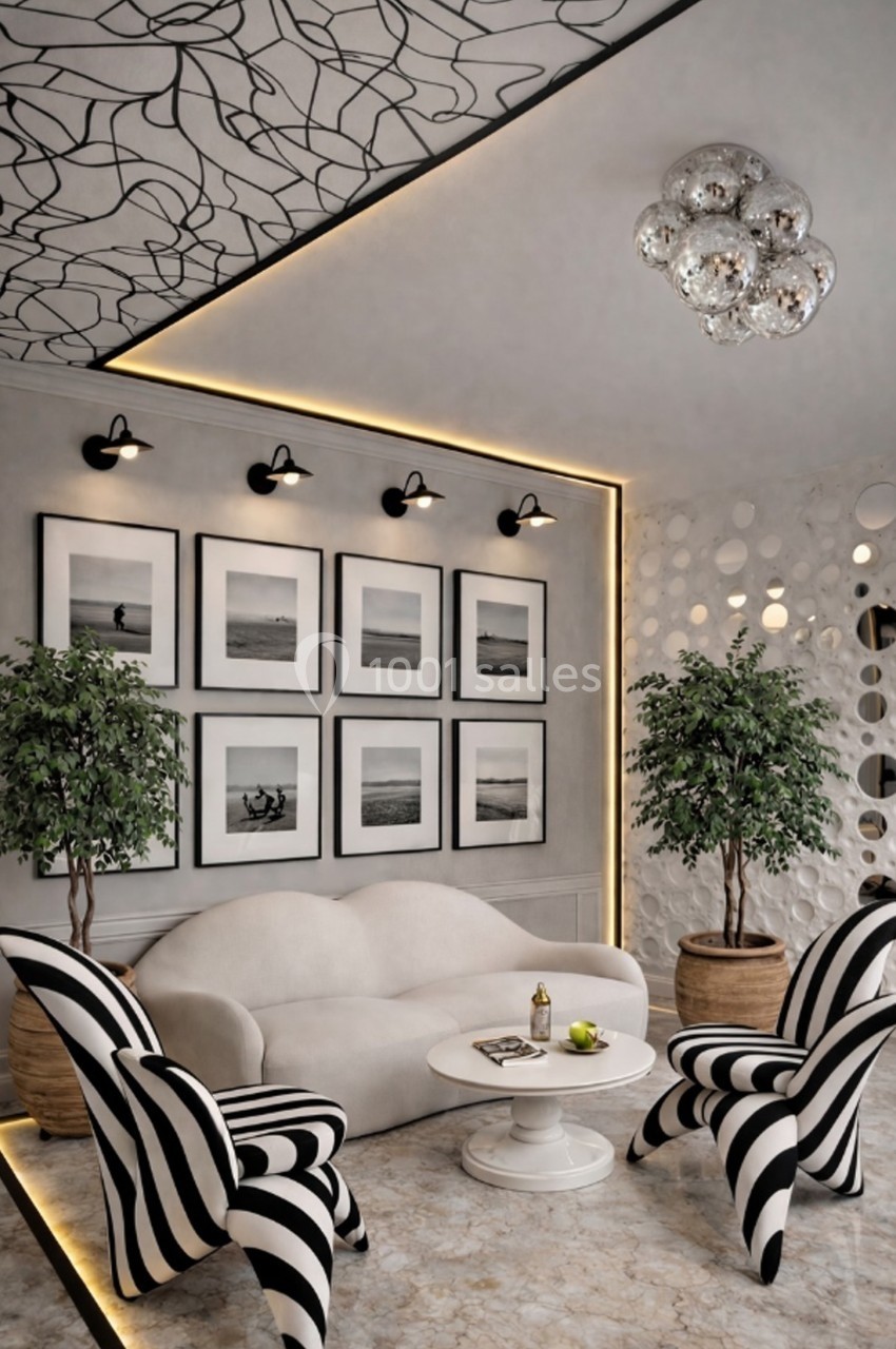 Salon moderne avec canapé blanc, fauteuils rayés noir et blanc, galerie de photos murale, plantes et éclairage design.