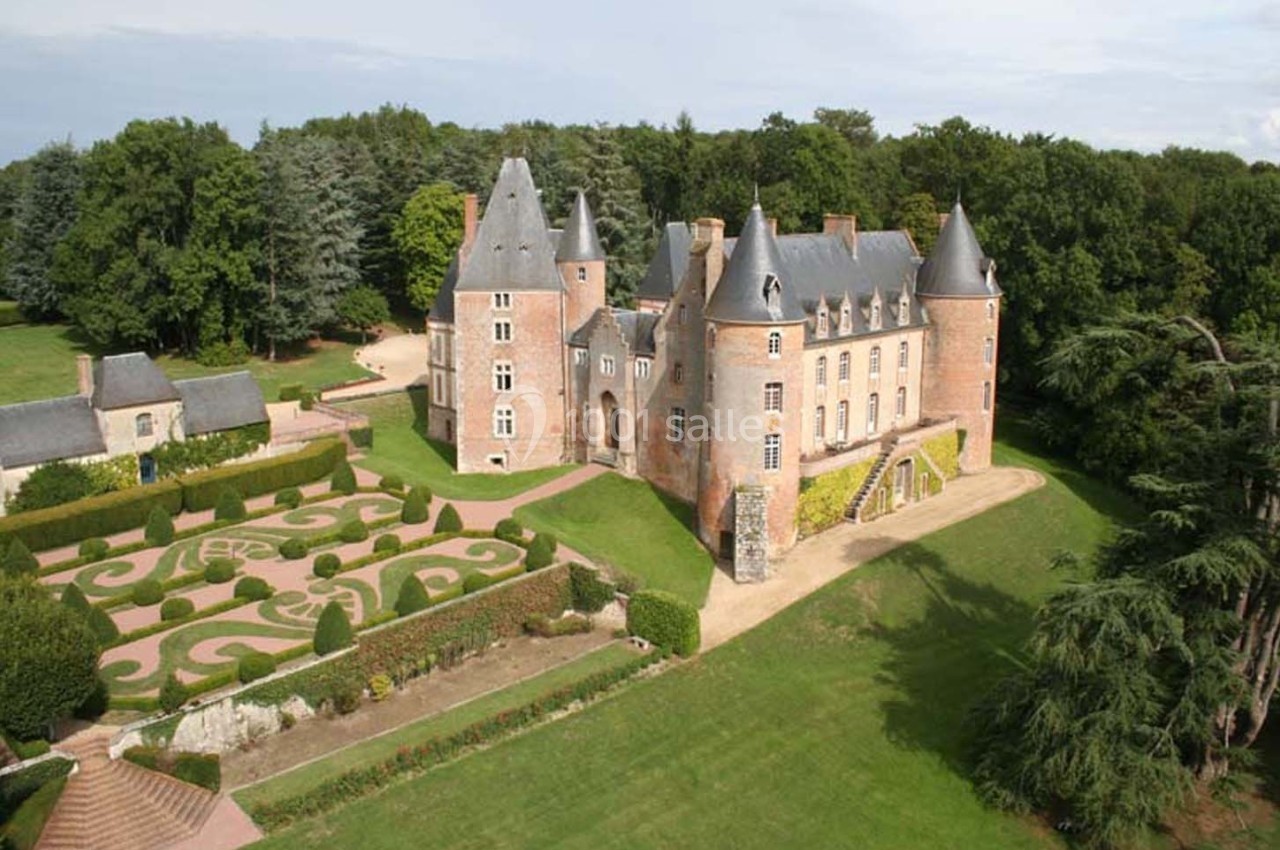 Vue aérienne d'un château en pierre entouré de jardins à la française et d'une forêt dense.