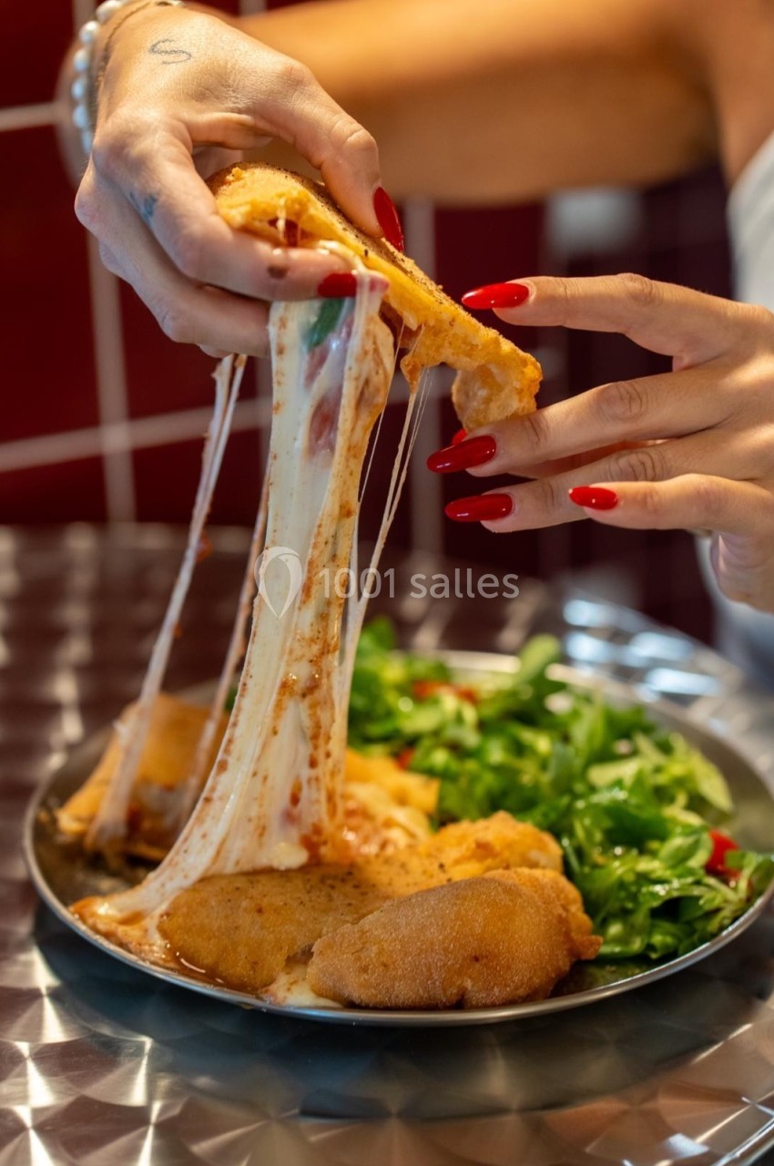 Plat de cordons-bleus avec fromage fondant, accompagné de salade verte, tenu par une main avec des ongles rouges.