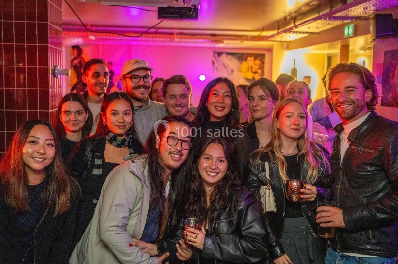 Groupe de personnes souriantes posant ensemble dans un espace intérieur avec éclairage coloré.