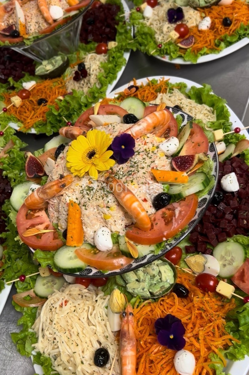 Plateau de crudités variées avec crevettes, légumes frais, fromage, fleurs comestibles et garnitures colorées.