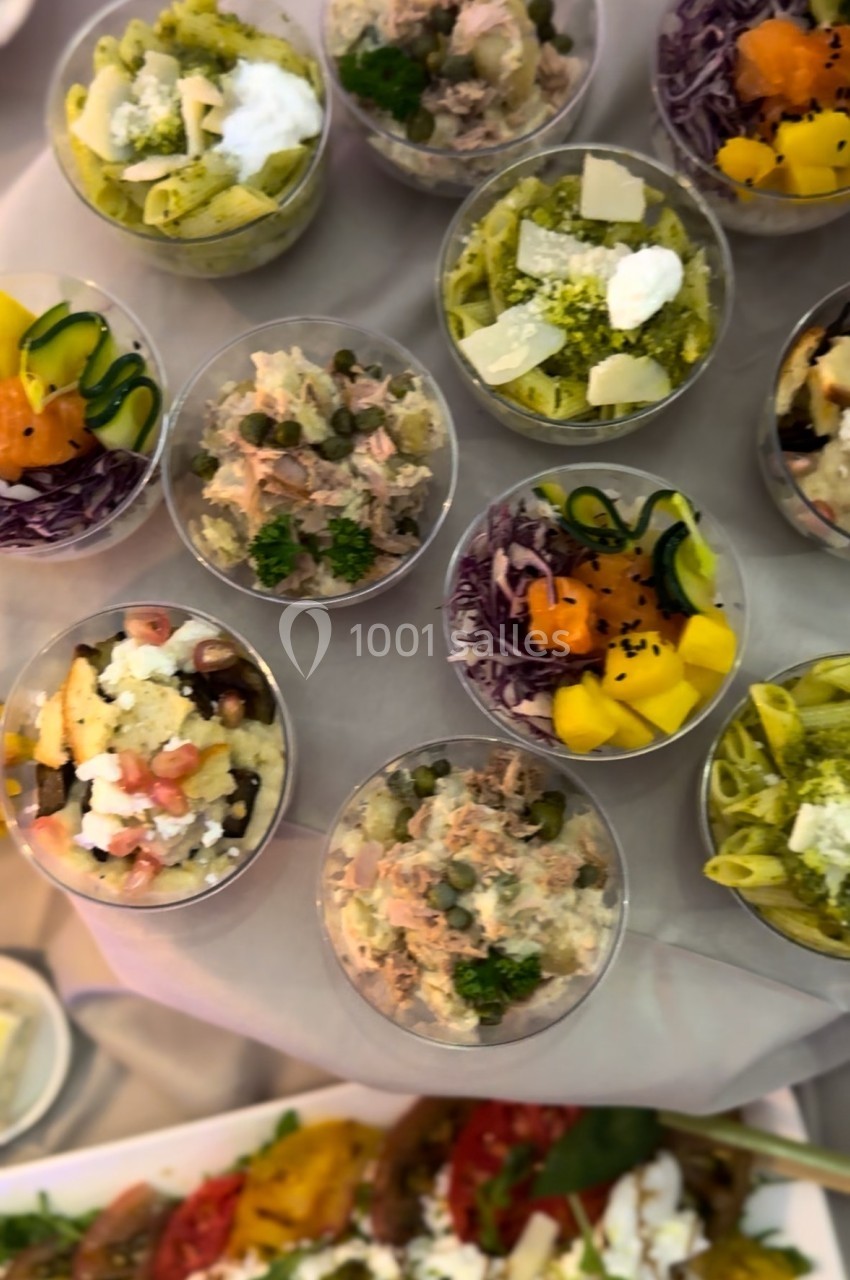 Assortiment de verrines colorées contenant des salades variées avec légumes, fromages et herbes fraîches.