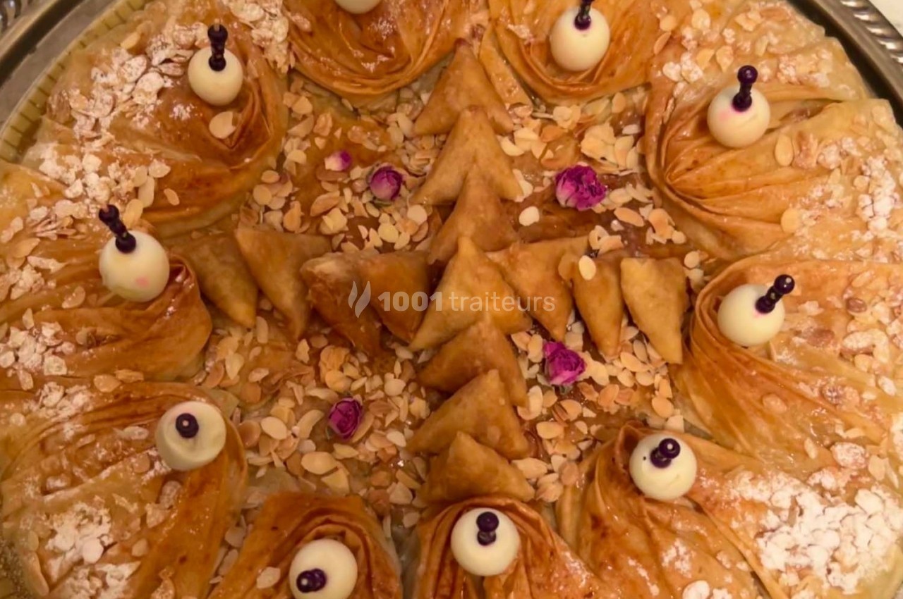 Assortiment de pâtisseries orientales en forme de triangles et spirales, décorées d'amandes, sucre glace et perles.