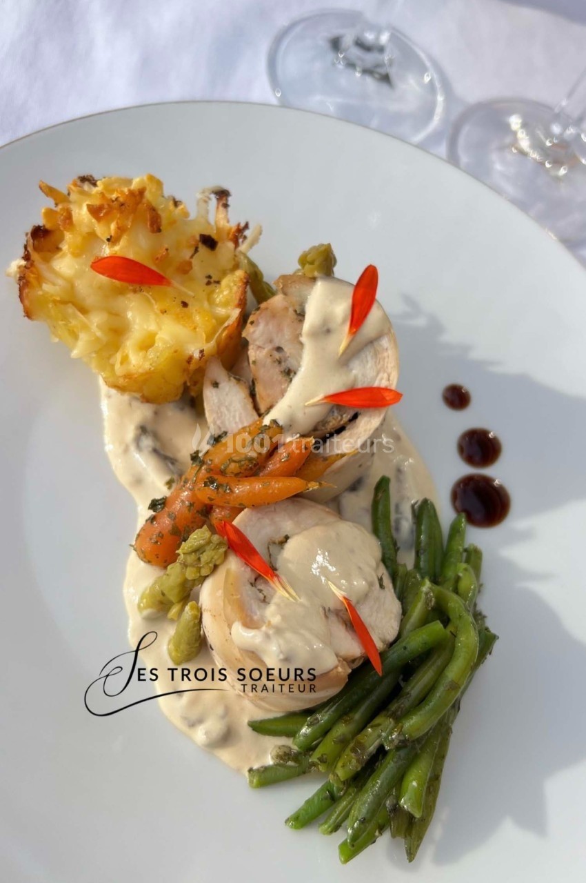 Assiette composée de volaille en sauce, haricots verts, gratin de pommes de terre et légumes décorés de piments rouges.