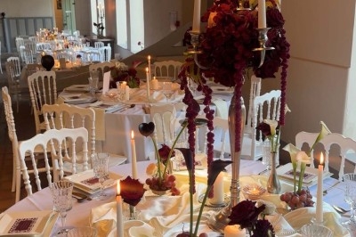 Miniature Traiteur Paris 8 (Paris) - Les Trois Soeurs Traiteur #41 Table de réception élégamment dressée avec chandeliers, fleurs pourpres et vaisselle raffinée dans une salle lumineuse.