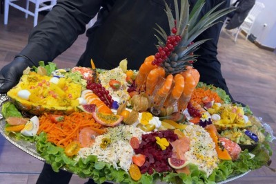 Table de réception élégamment dressée avec chandeliers, fleurs pourpres et vaisselle raffinée dans une salle lumineuse.