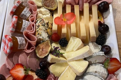 Table de réception élégamment dressée avec chandeliers, fleurs pourpres et vaisselle raffinée dans une salle lumineuse.