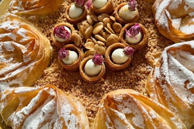 Table de réception élégamment dressée avec chandeliers, fleurs pourpres et vaisselle raffinée dans une salle lumineuse.
