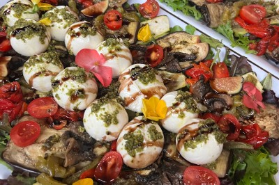 Table de réception élégamment dressée avec chandeliers, fleurs pourpres et vaisselle raffinée dans une salle lumineuse.