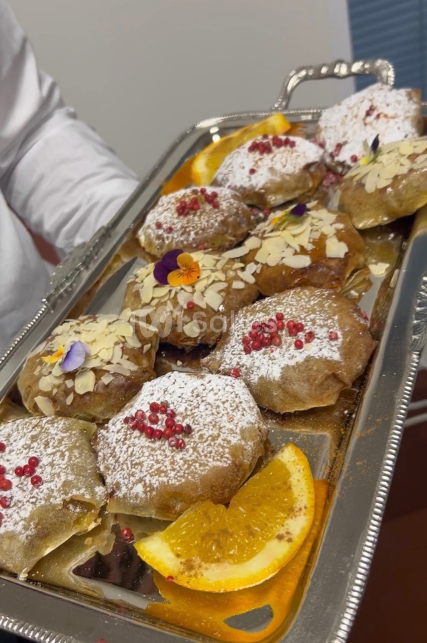 Plateau de pâtisseries garnies de sucre glace, amandes effilées, baies rouges et fleurs comestibles, avec des tranches d…